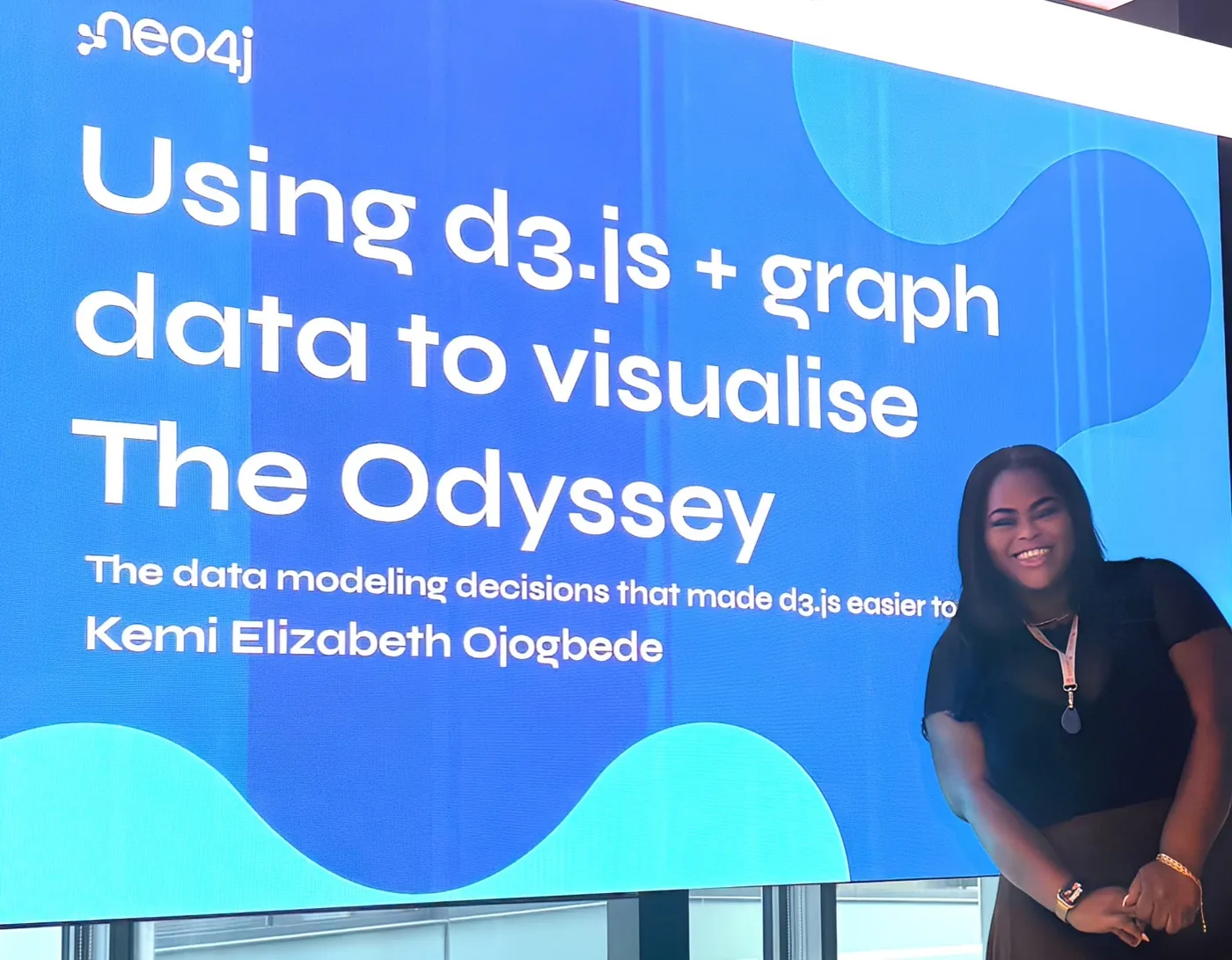 Kemi smiling in front of the title slide for her talk